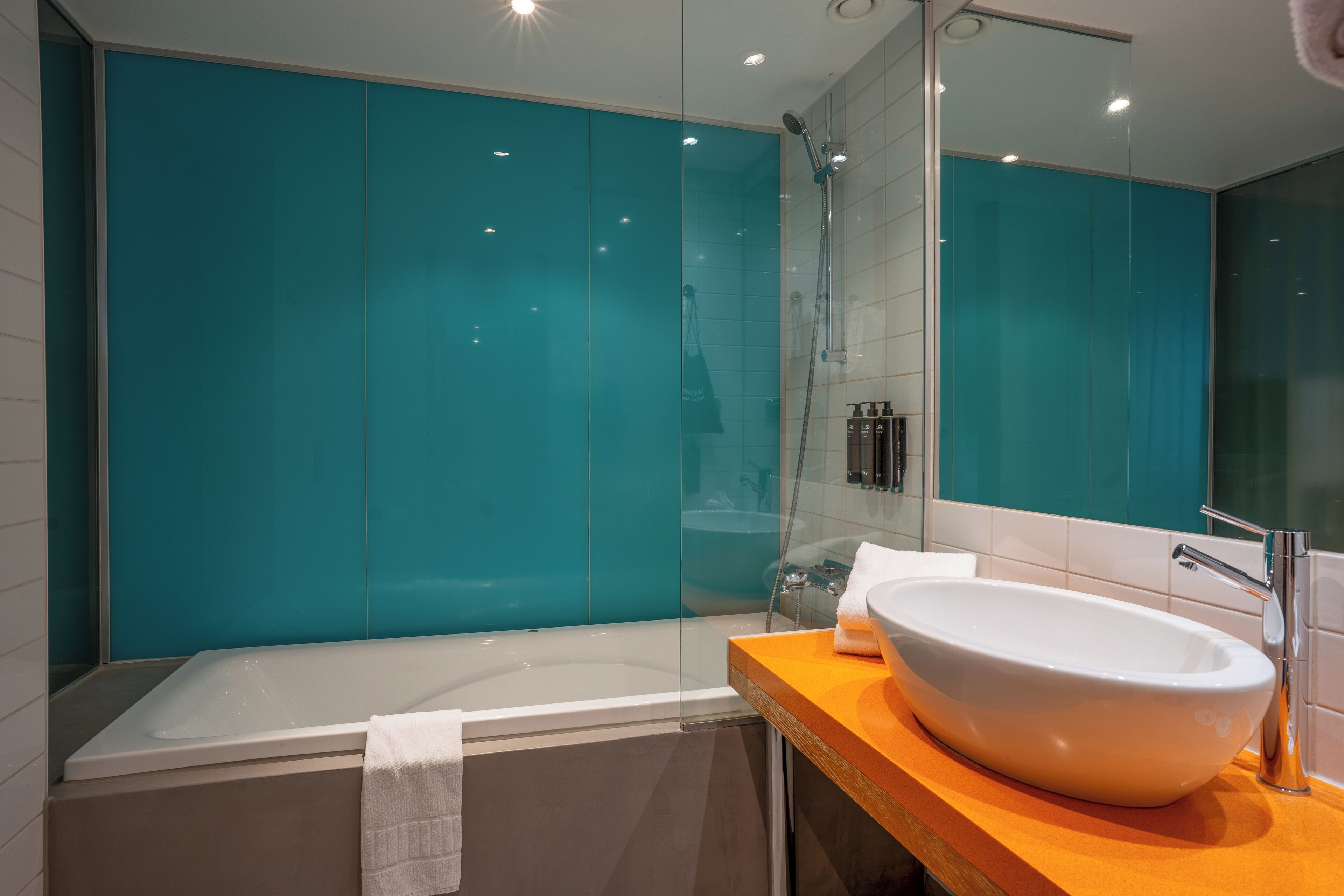 A modern bathroom with a large bathtub, a white sink, and a glass shower enclosure.