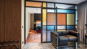 Een moderne hotelkamer met een schuifdeur naar een balkon, een bank en een klein tafeltje.