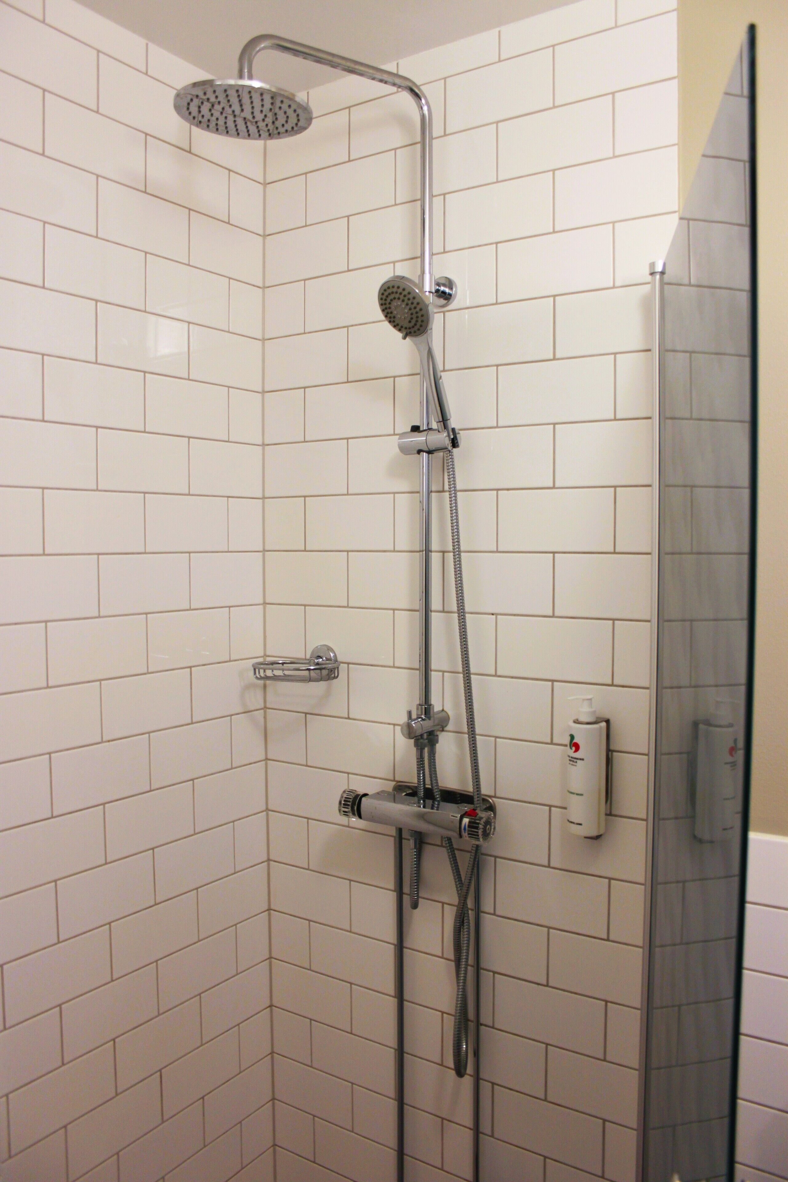 Ducha con cabezal de ducha de mano, grifo empotrado en la pared y panel de control.