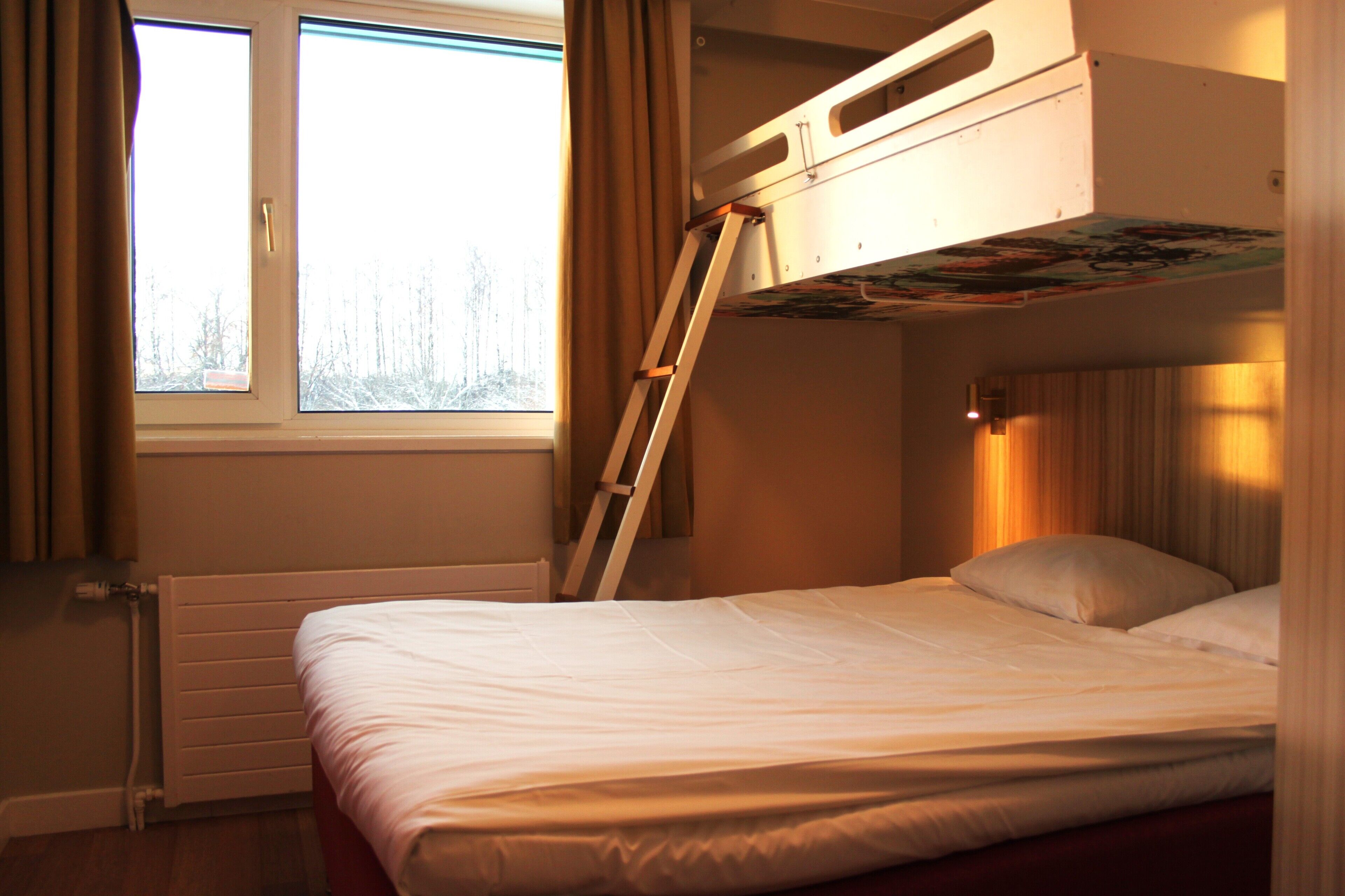 Quarto com beliche, uma escada, janela com cortinas e radiador.
