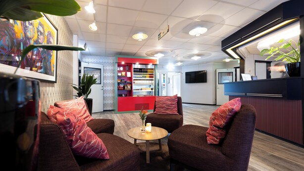 En entréhall med sittplatser, en receptionsdisk och en automater för försäljning av varor.