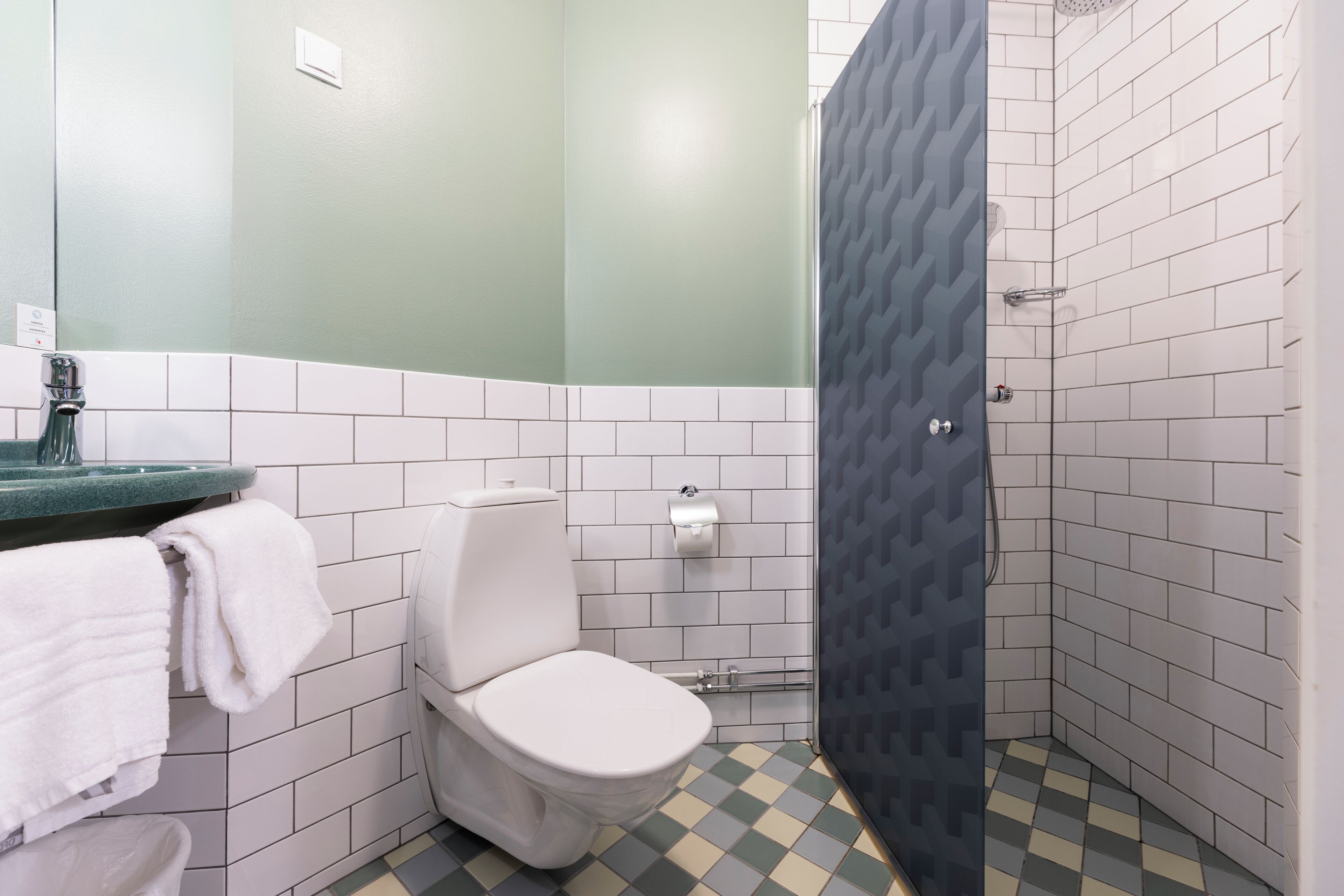 A bathroom with a toilet, sink, and shower area.