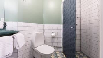A bathroom with a toilet, sink, and shower area.