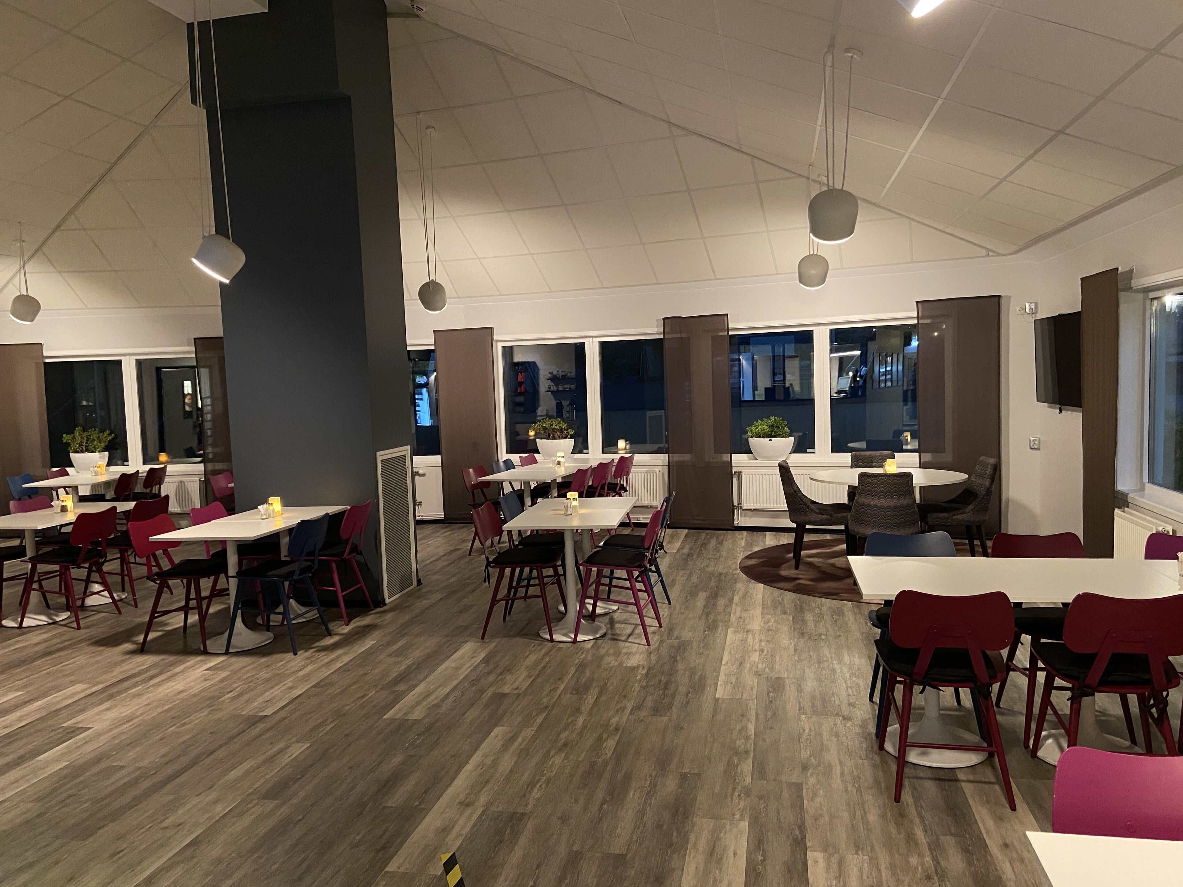 A modern restaurant with multiple dining areas, including a central round table and several rectangular tables.