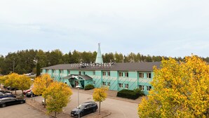A turquoise building with a sign reading "GOOD MORNING HOTELS" and a small tower-like structure on the roof.
