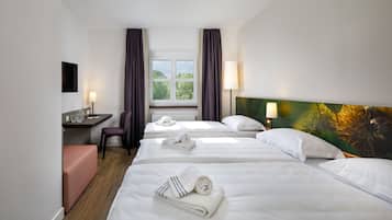 Ein Hotelzimmer mit zwei Betten, einem Schreibtisch, einem Stuhl und einem Fenster mit Vorhängen.