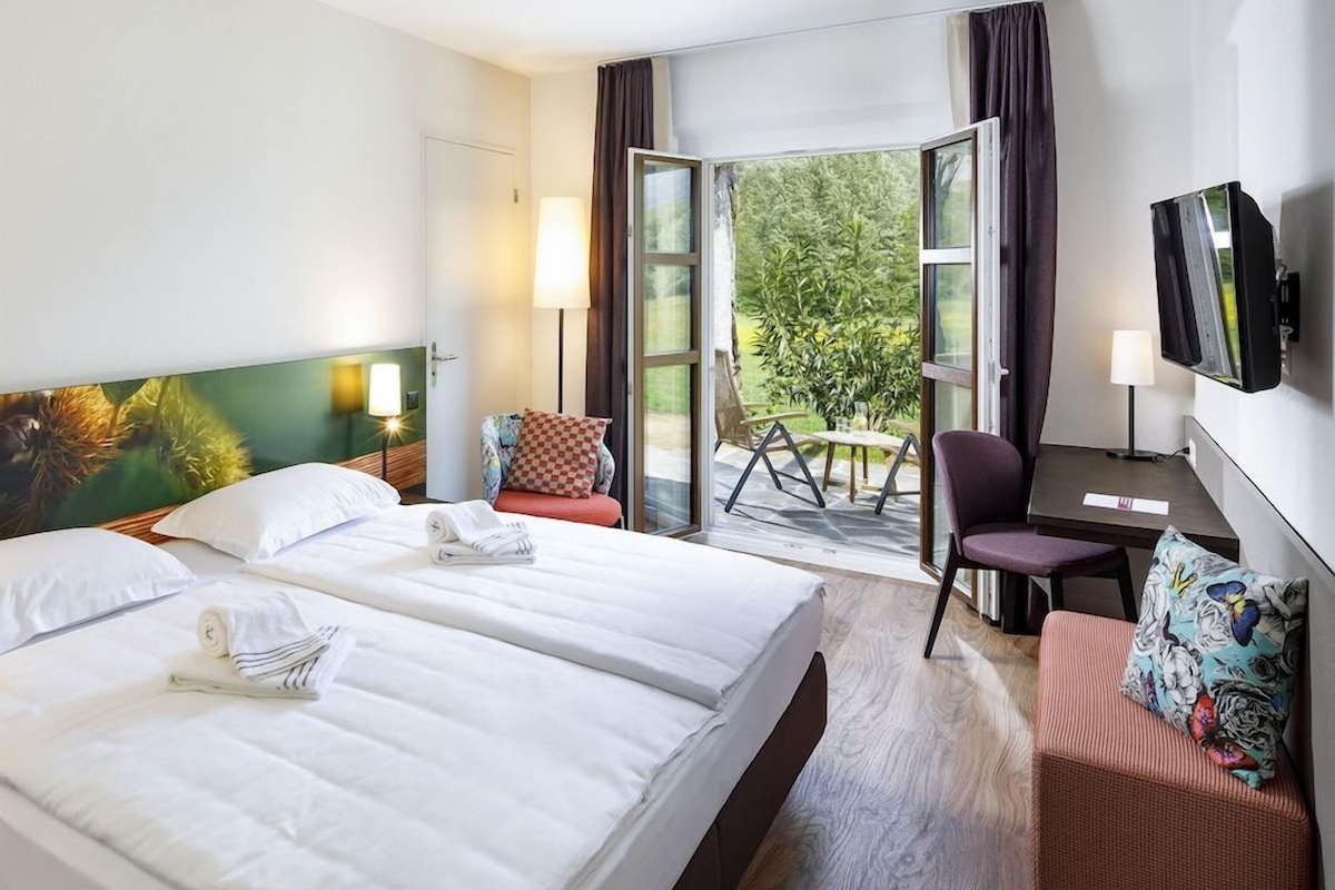 Een hotelkamer met twee bedden, een bureau, een stoel en een televisie.