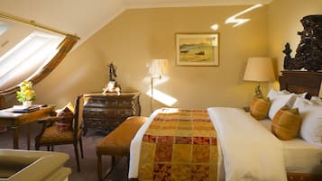 Una habitación de hotel con una cama, un escritorio, una silla, un aparador y una lámpara.