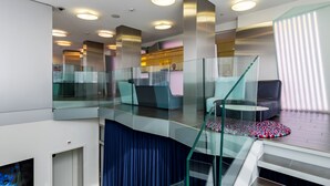 A modern interior with a glass staircase, a seating area, and a kitchen visible in the background. - Hotel Cristal (Geneva)