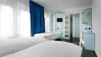 Ein modernes Hotelzimmer mit zwei Betten, einem Schreibtisch und einem Fernseher.
