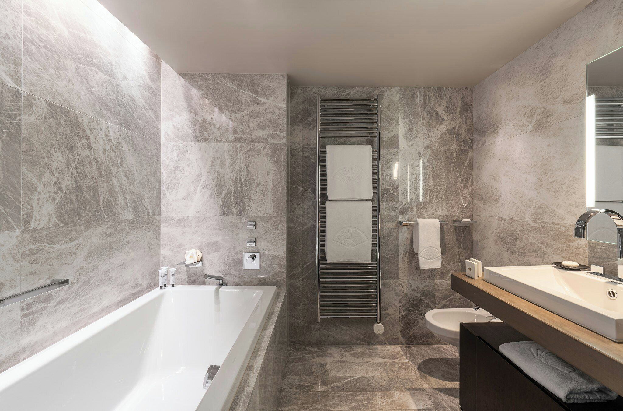 A modern bathroom with a freestanding bathtub, a vanity with a mirror, and a toilet.