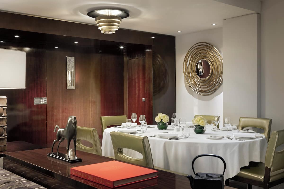 A dining area with a round table set for four, surrounded by leather chairs.