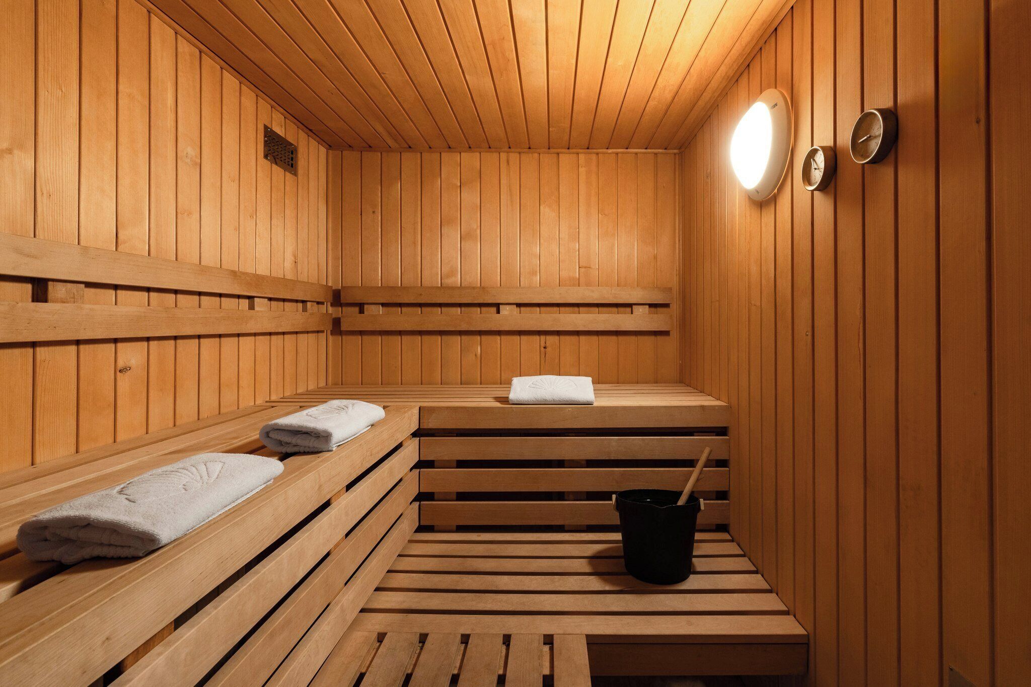 Uma sauna de madeira com bancos, uma toalha e um balde.