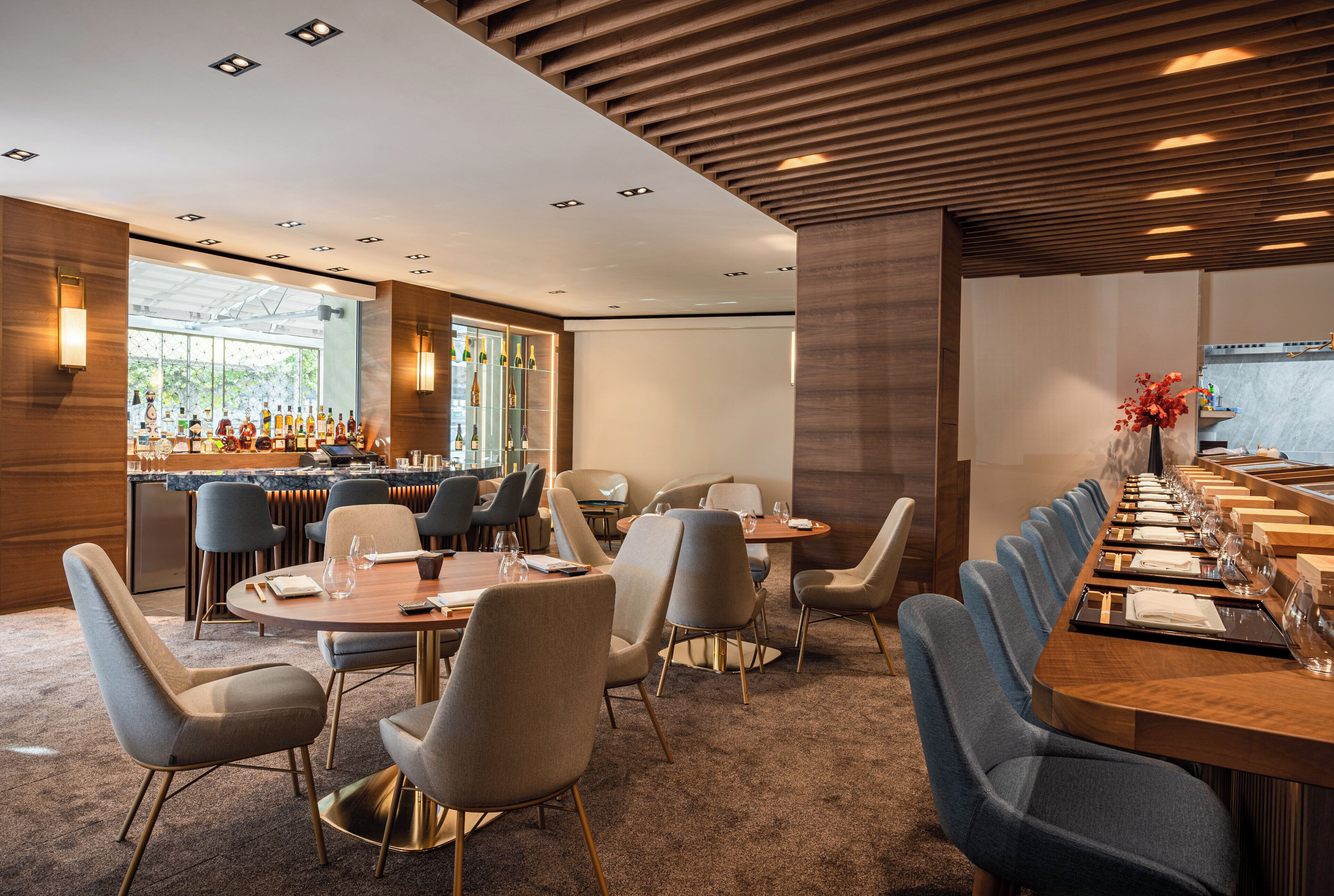 Ein moderner Hotel-Speiseraum mit runden Tischen, einer Bar und Sitzgelegenheiten.