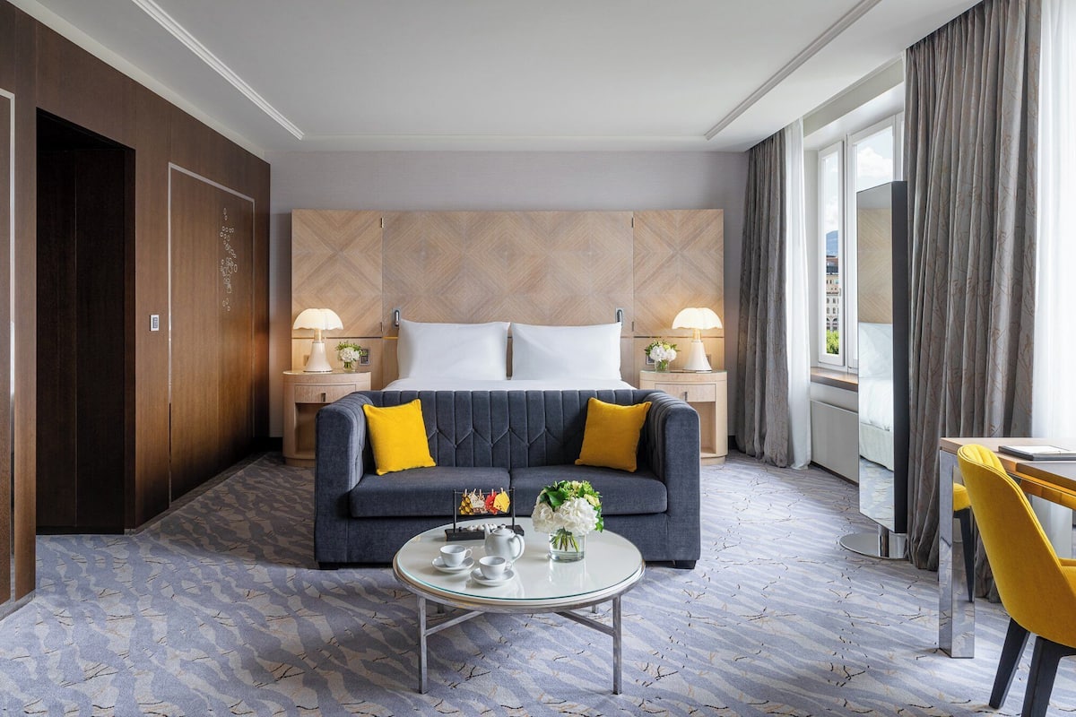 Una habitación de hotel con una cama, un sofá, una mesa de centro y un área de comedor.