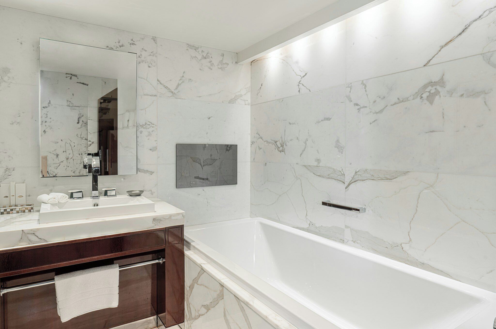 Un baño moderno con un lavabo de mármol, un espejo grande y una bañera.