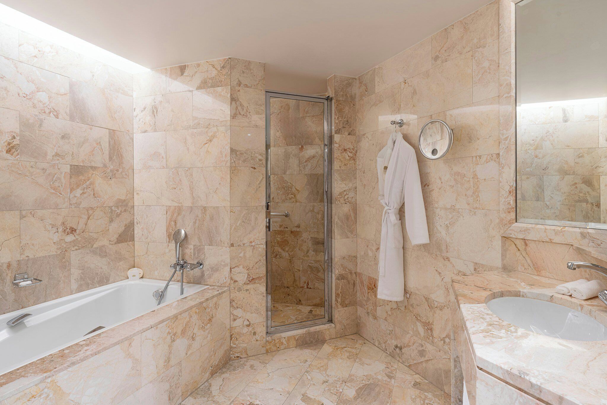 A bathroom with a glass-enclosed shower, a bathtub, and a sink.