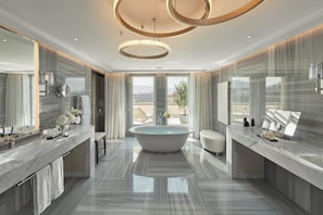 A modern bathroom with a freestanding bathtub, large mirrors, and a marble countertop.