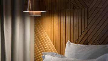 Ein Schlafzimmer mit einer Wand aus Holzlatten, einer Pendelleuchte und einem Bett mit weißer Bettwäsche.