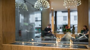 Un área de recepción moderna con separador de vidrio, mostrador de madera y lámparas decorativas.