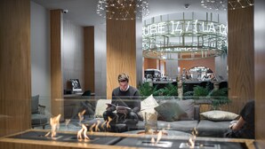 Un espacio lounge moderno con chimenea, asientos cómodos y un bar al fondo.