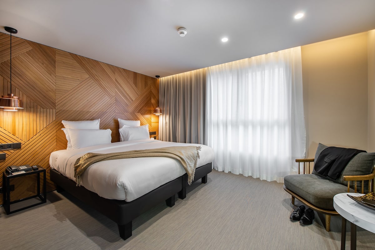 Moderni hotellihuone, jossa on suuri sänky, sohva ja pieni pöytä.