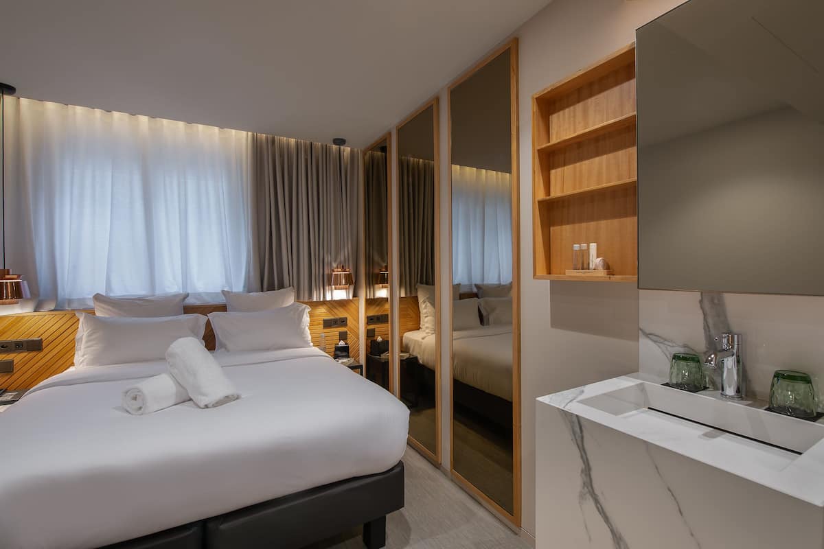 Hotellihuone, jossa on suuri sänky, erillinen vaatehuone, peilillä varustettu meikkipöytä ja pieni oleskelualue.
