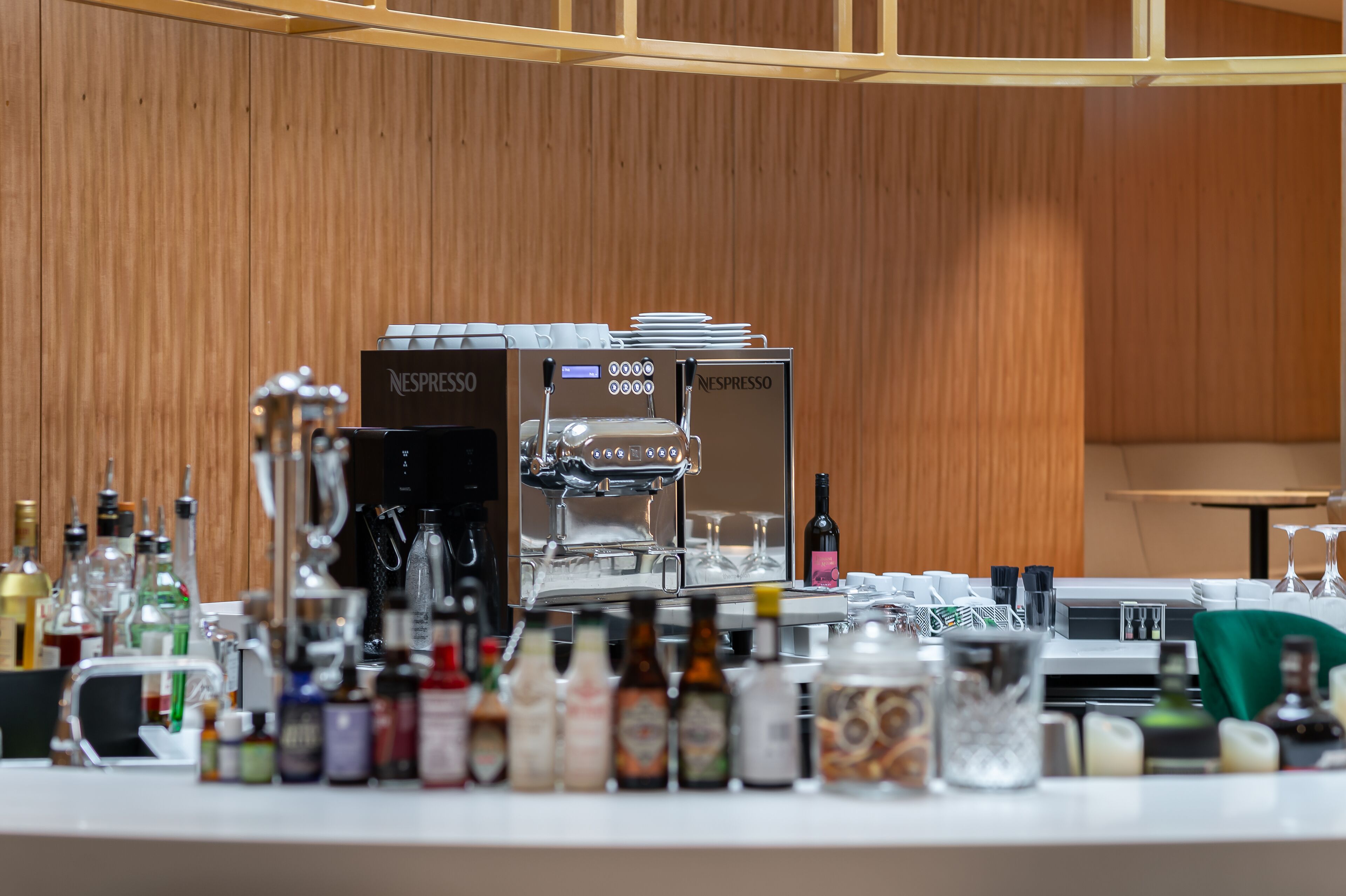 A bar area with a Nespresso coffee machine, various bottles of alcohol, and glasses.