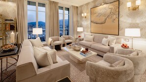 A spacious living room with a large window, a sofa set, a coffee table, and a decorative painting. - Hotel d'Angleterre Geneva (Geneva)