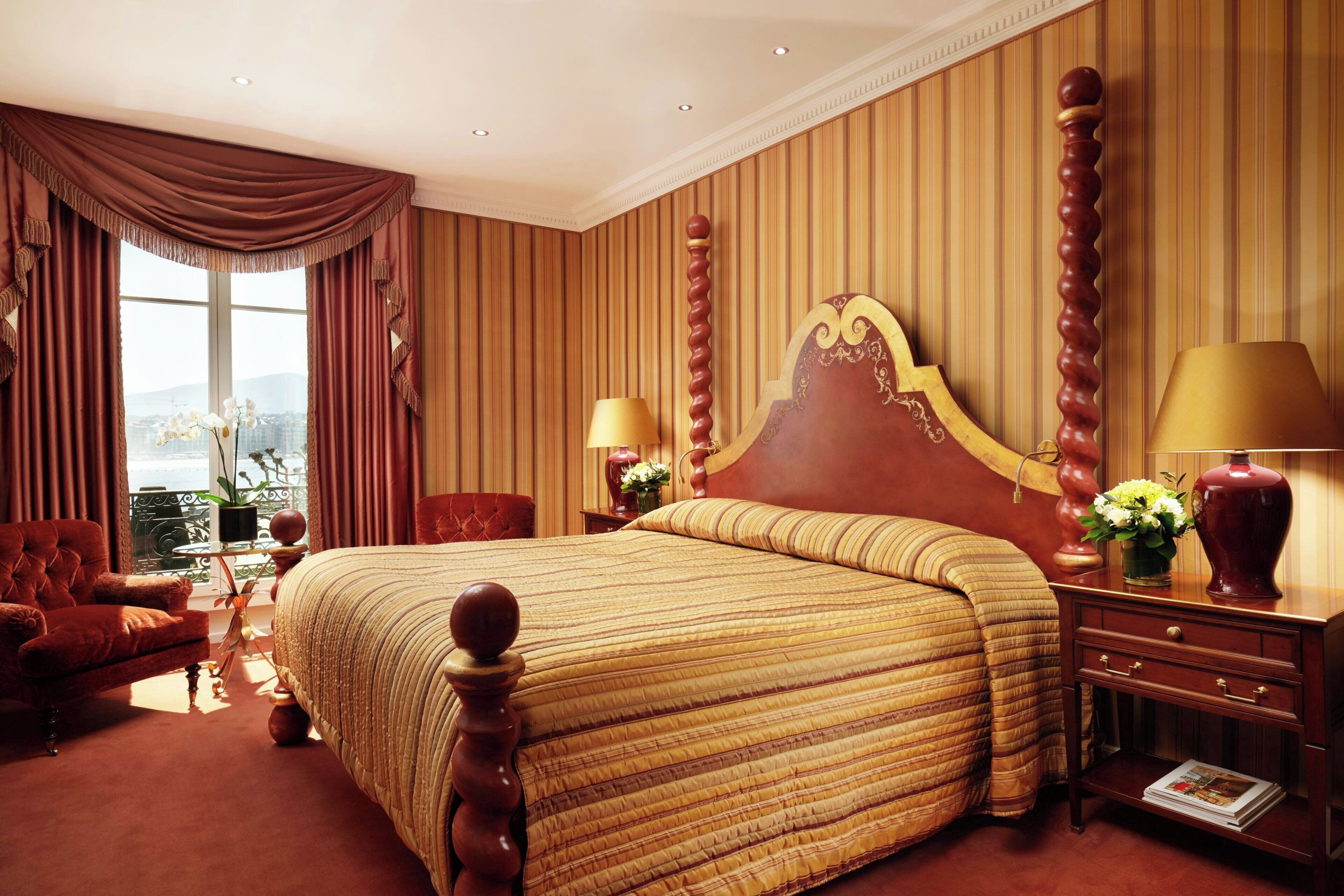 A hotel room with a large bed, a chair, a nightstand, and a view of the city.