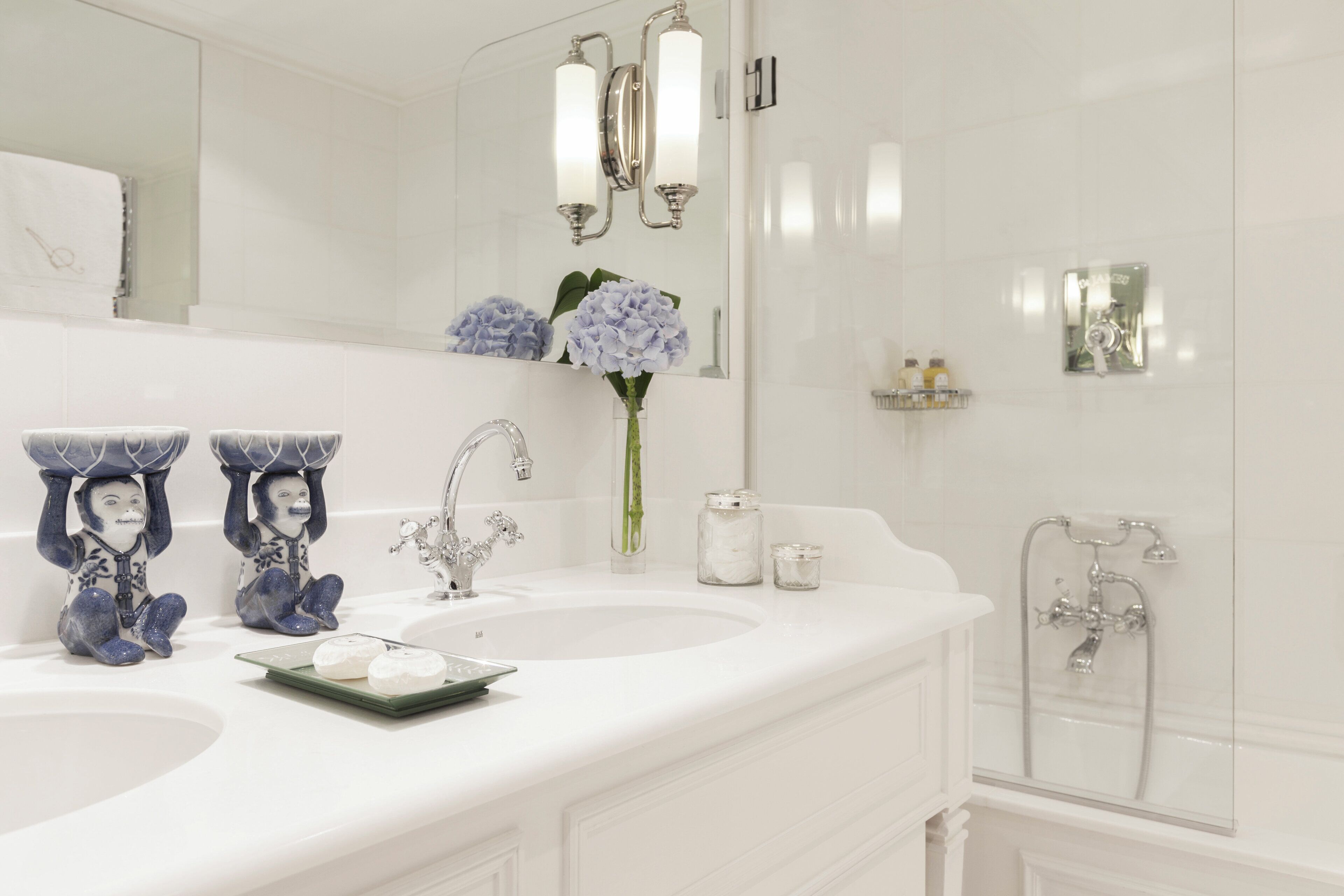 Een badkamer met twee wastafels, een spiegel en een douche.