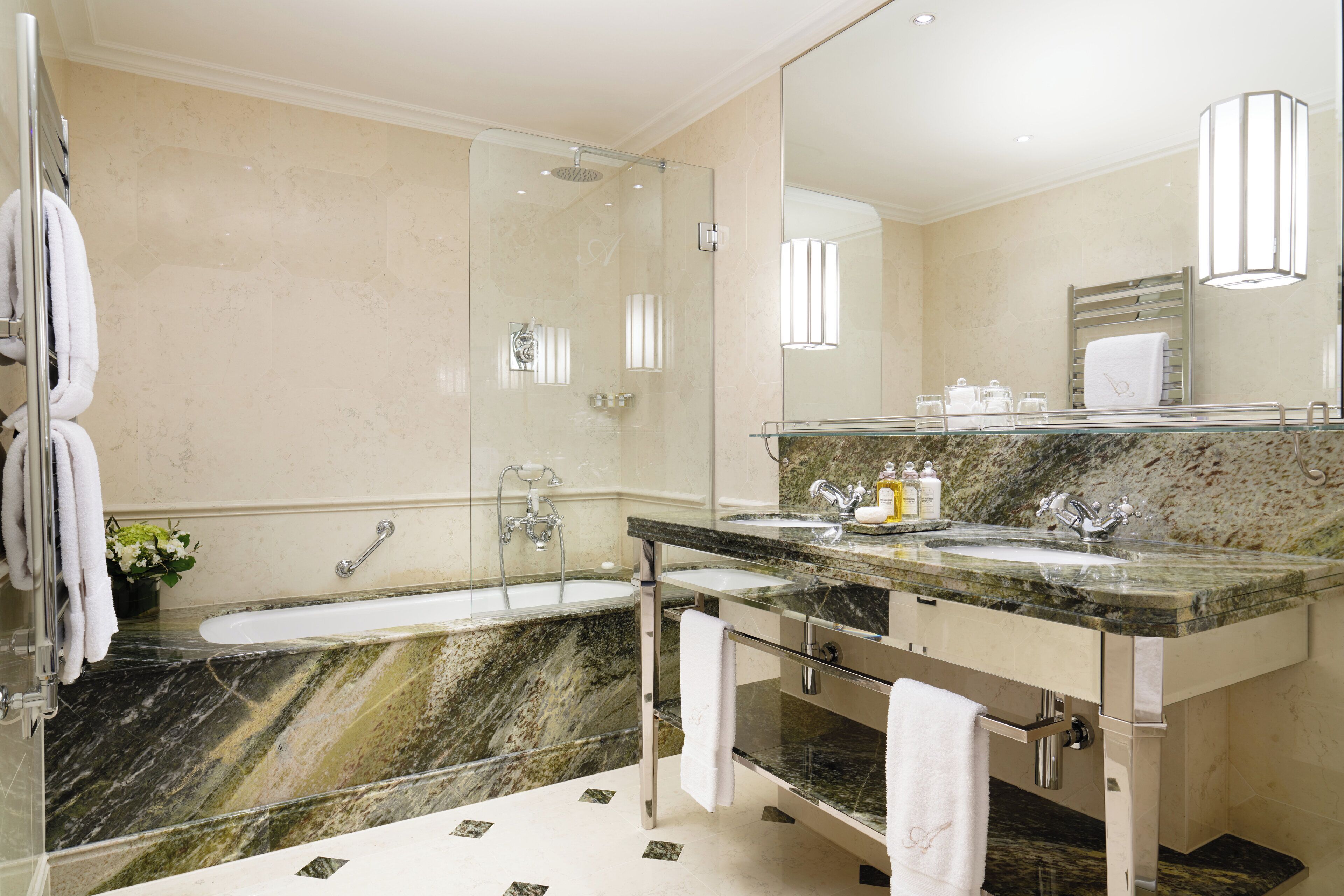 A modern bathroom with a glass-enclosed shower, a marble sink, and a large mirror.