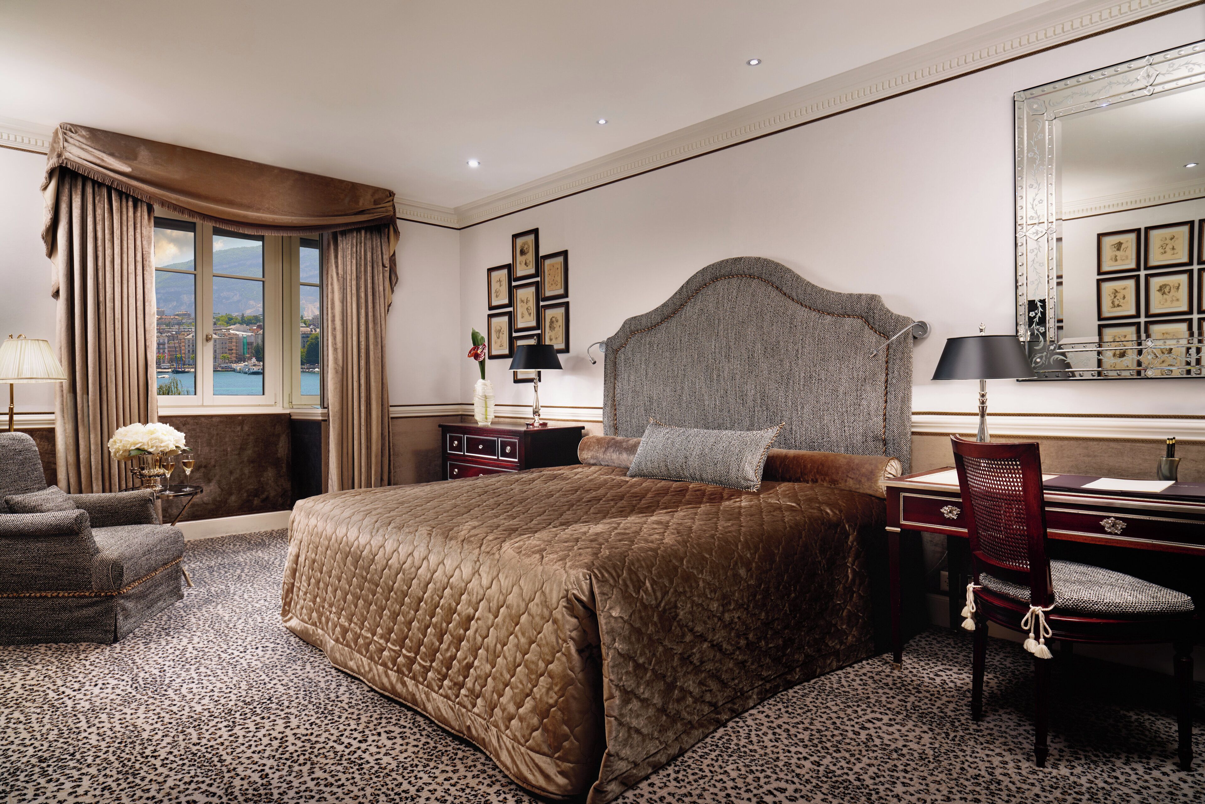 Una habitación de hotel con una cama grande, un escritorio con una silla, un aparador y un espejo amplio.
