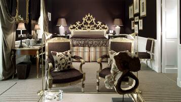 A luxurious bedroom with a large bed, ornate headboard, and classic furniture.