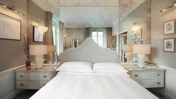 A hotel room with a large bed, two bedside tables, a mirror, and wall-mounted lamps.