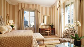 A hotel room with a large bed, a desk, a chair, and a view of the city.