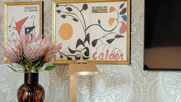 A desk with a vase of flowers, framed artwork, and a chessboard.