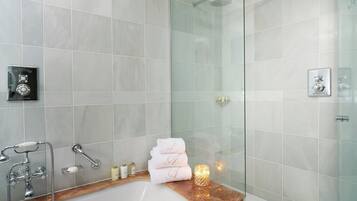 Un bany modern amb dutxa de vidre, un lavabo de marbre i tovalloles ordenadament doblegades.