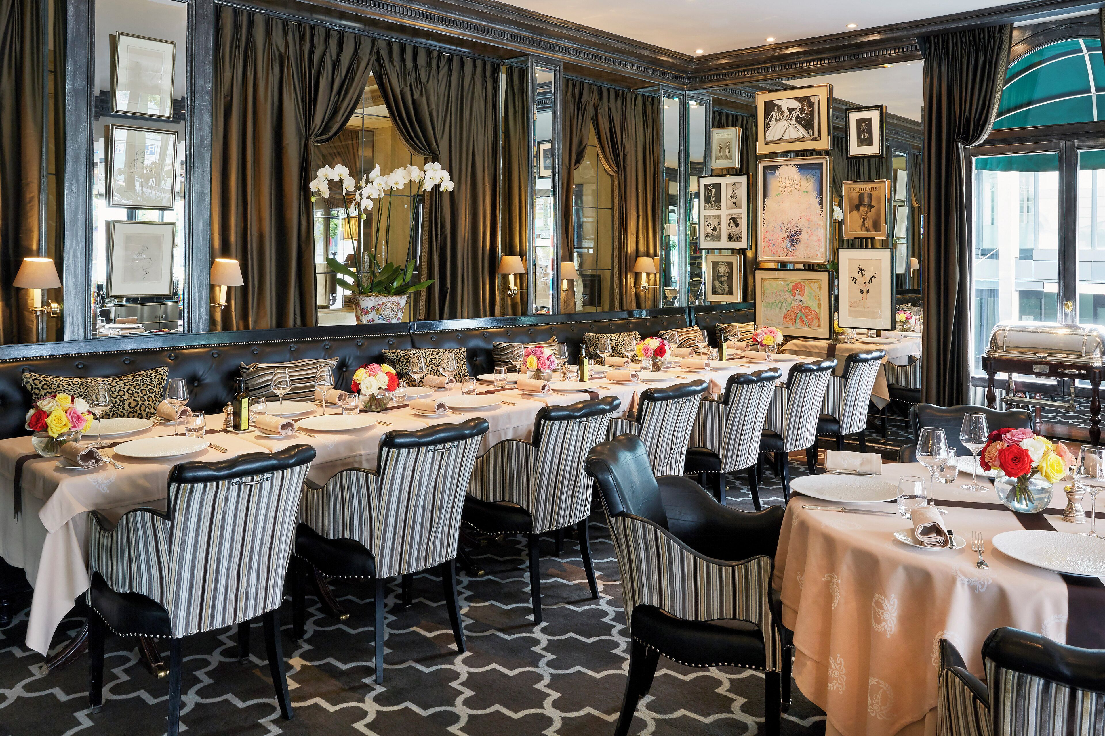 A formal dining room with striped chairs, a long table set for a meal, and a large mirror reflecting the room.