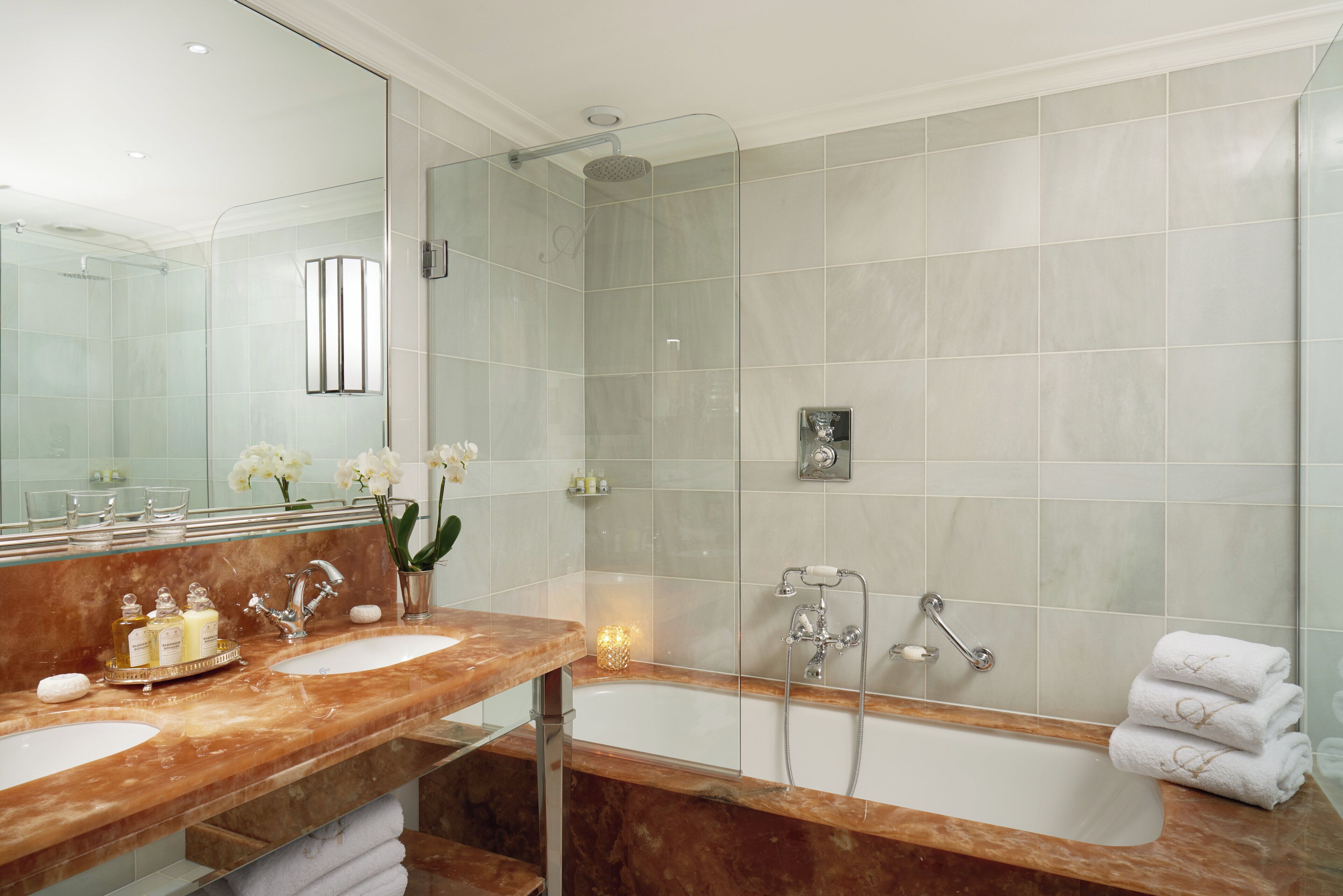 A modern bathroom with two sinks, a glass-enclosed shower, and a large bathtub.