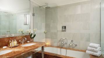 A modern bathroom with two sinks, a glass-enclosed shower, and a large bathtub.