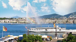 A river with a boat, buildings, and a fountain. - Hotel d'Angleterre Geneva (Geneva)