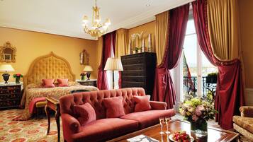 A luxurious bedroom with a large bed, a red sofa, a wooden coffee table, and a dresser.