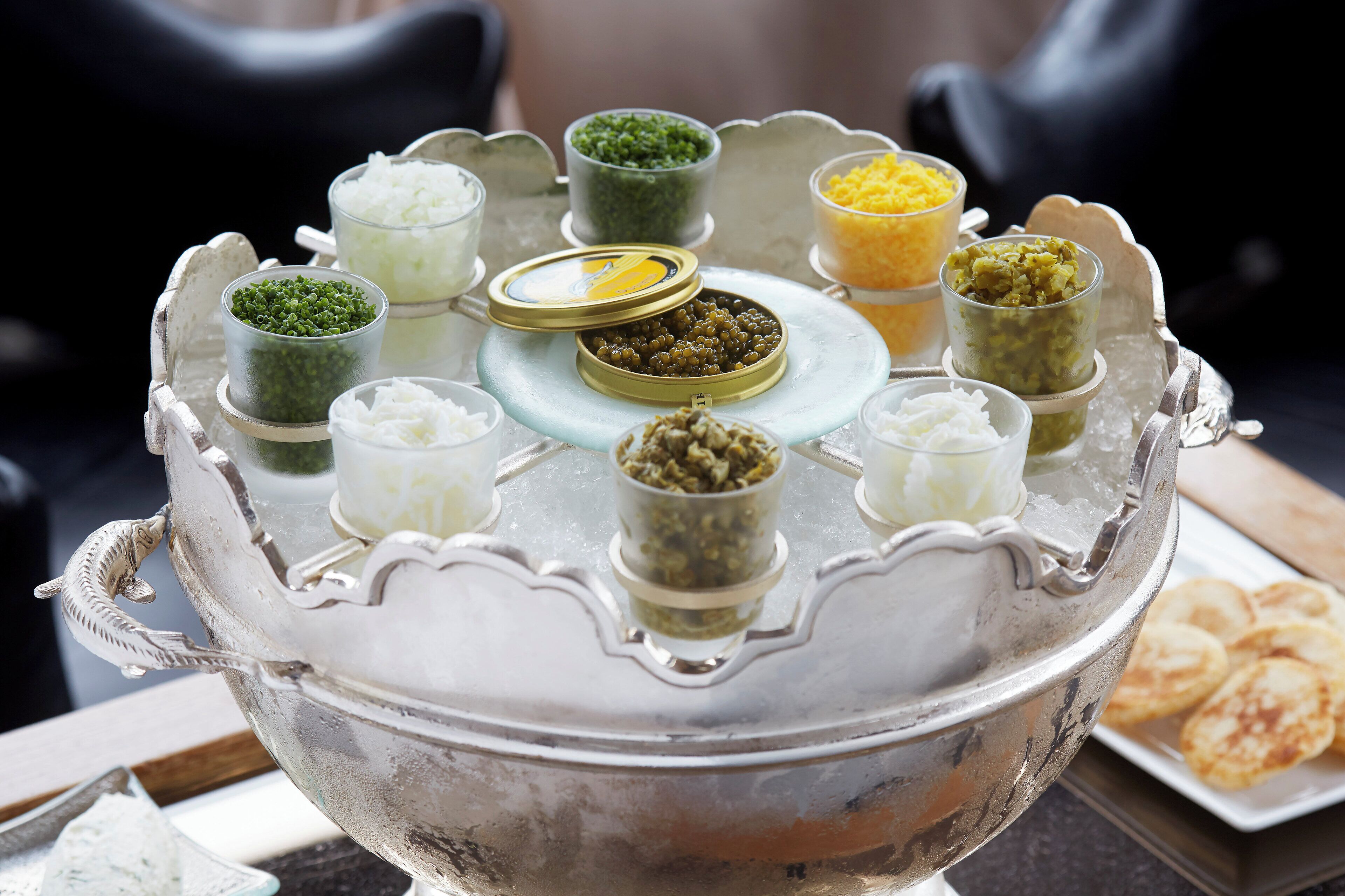 A silver serving tray with multiple small containers of pickled vegetables and a plate of crackers.