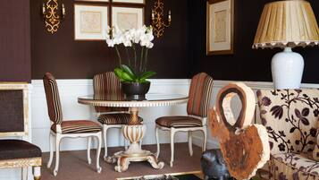A room with a round table, striped chairs, a sofa, and a decorative lamp.