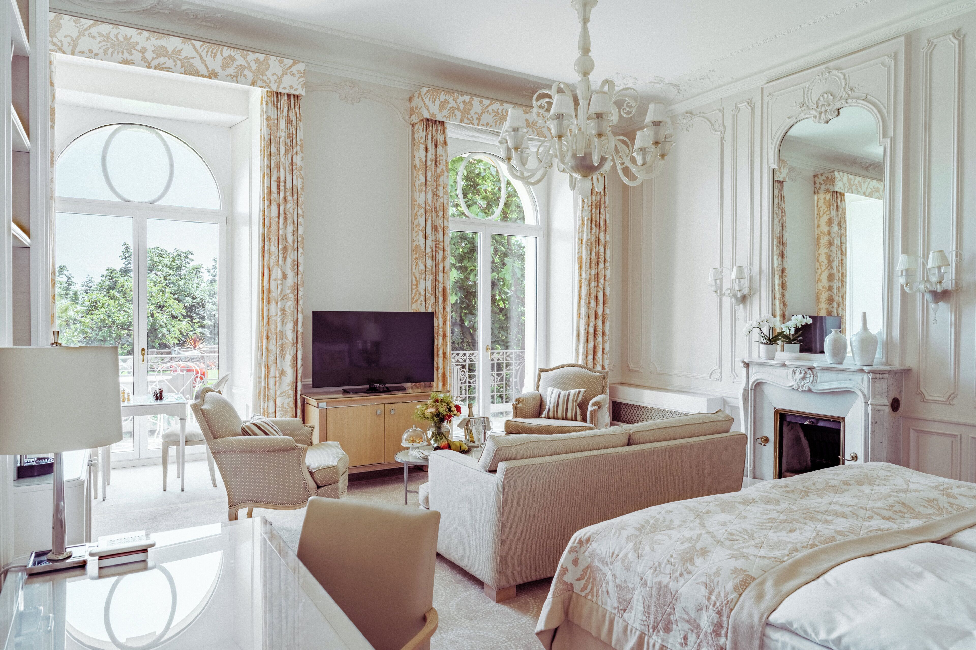 A hotel room with a bed, sofa, TV, and a fireplace.