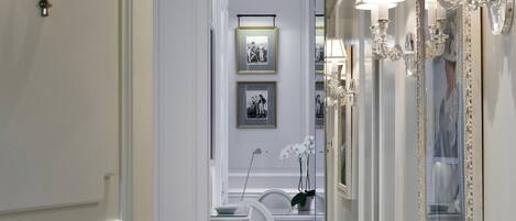 A hallway with a white door, a marble floor, and a dining area with a white table and chairs.
