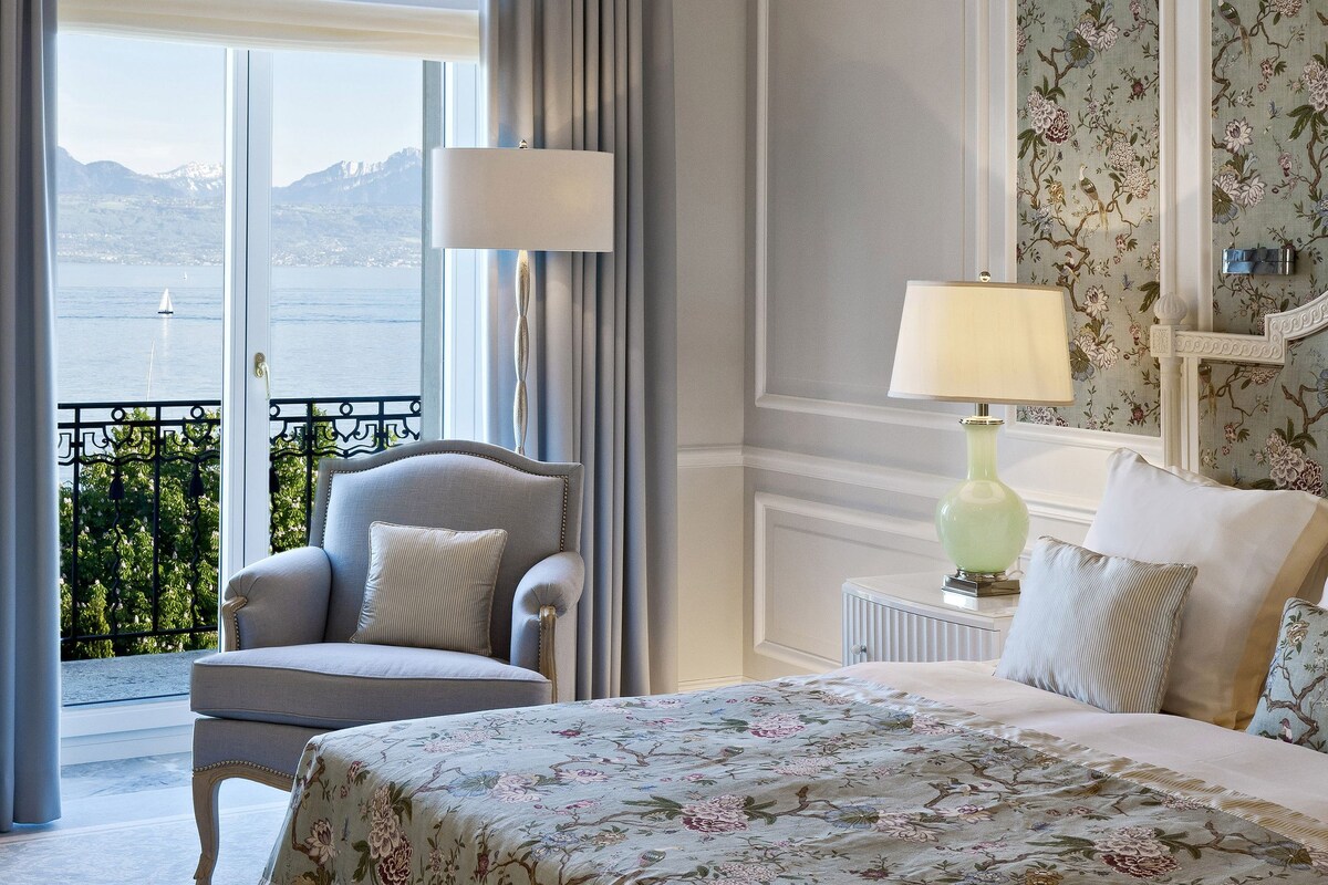 Un dormitorio con una cama grande, un candelabro, vistas al mar y un balcón.