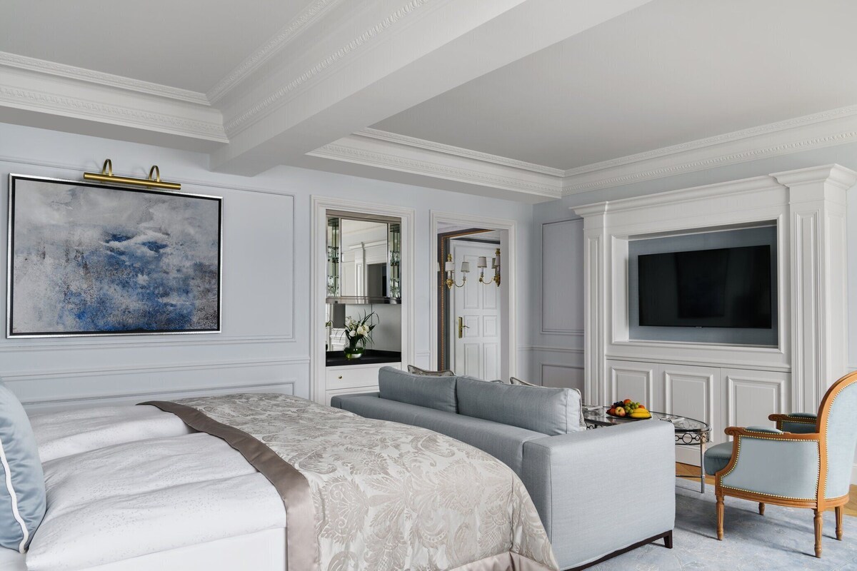 Une chambre à coucher avec un lit, un canapé, une télévision et un fauteuil.