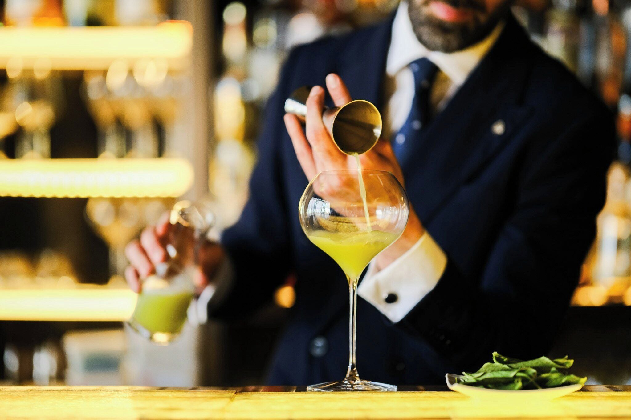 Un barman sirviendo una bebida en una copa de martini.